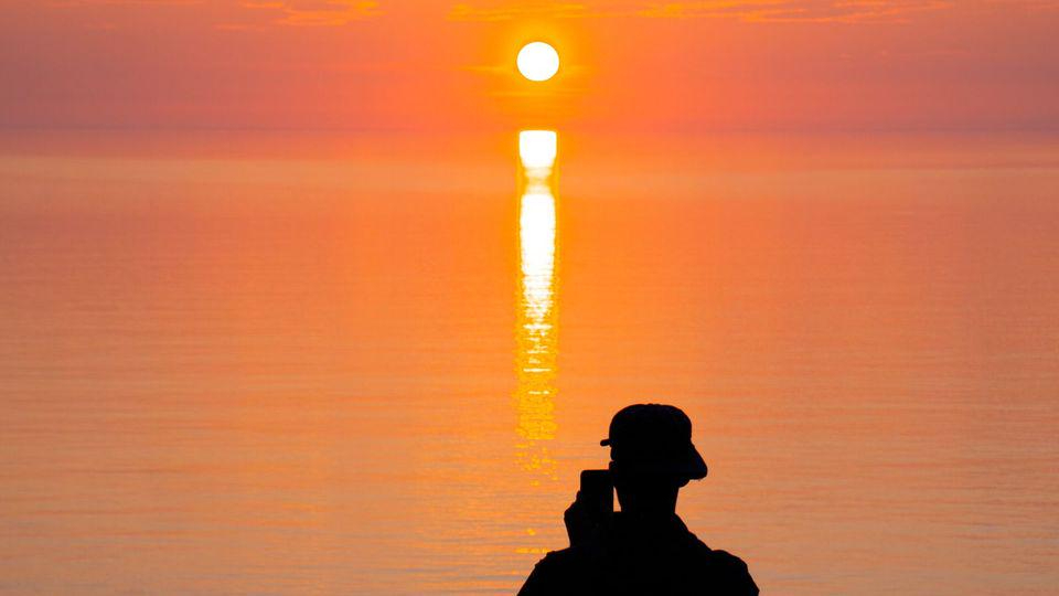 Silhouette fotografiert mit dem Handy den Sonnenuntergang